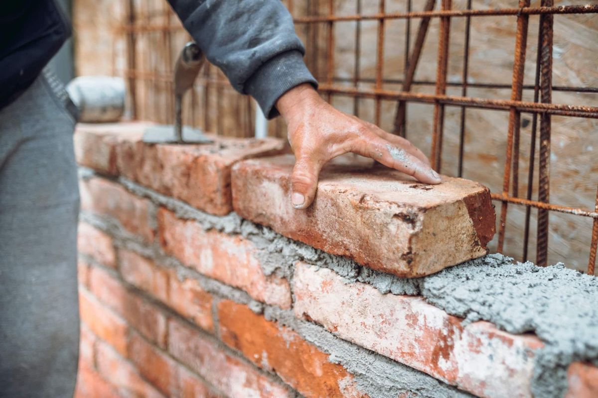 Maurer setzt Ziegel mit Mörtel auf einer Baustelle