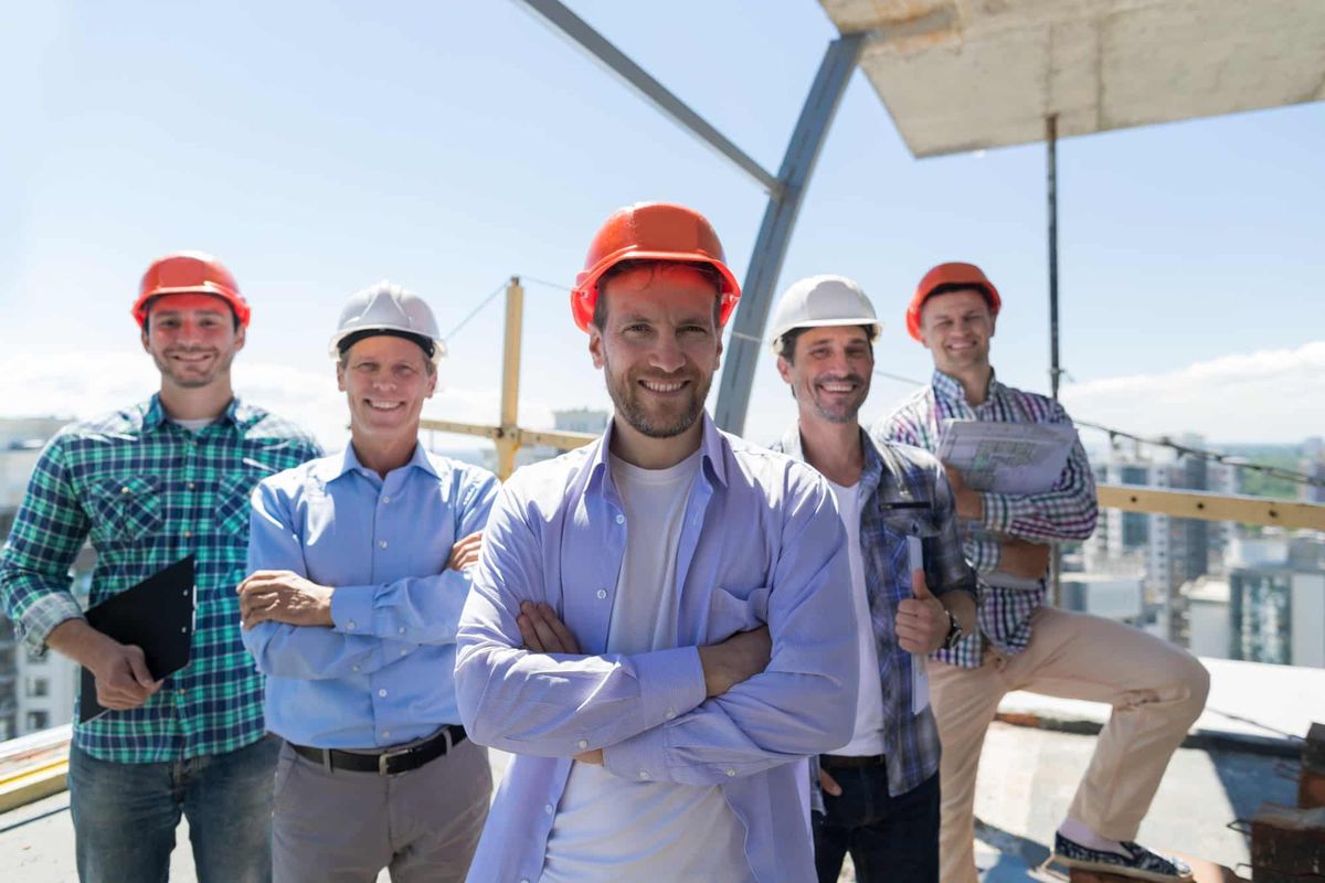 Zufriedenes Bau-Team der TD BAU & Personalservice mit Schutzhelmen auf der Baustelle